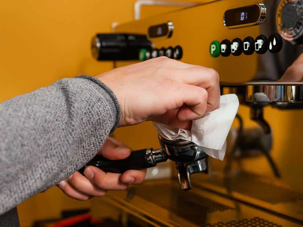 barista doet onderhoud aan een pistonmachine